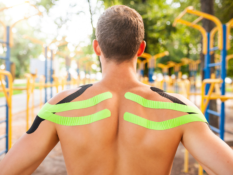 Atleta con kinesio tape sulle spalle in un parco attrezzato per l’allenamento
