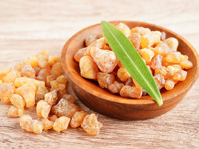 Grani di resina di Boswellia in ciotola di legno, con foglia verde decorativa