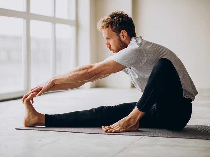 Uomo in abbigliamento sportivo fa stretching a terra dopo l’allenamento