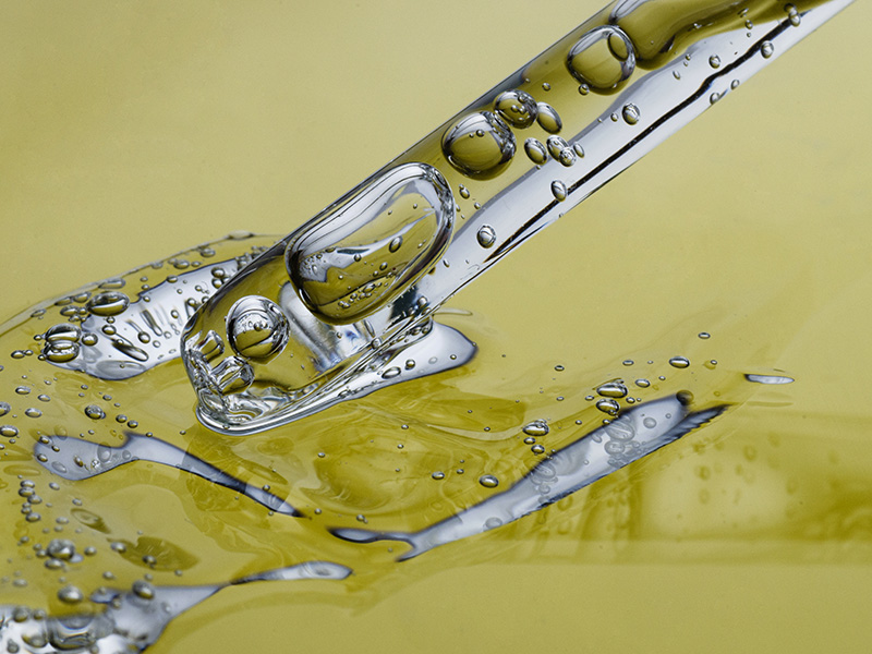 Dettaglio di contagocce con olio ozonizzato Reloil su fondo giallo chiaro