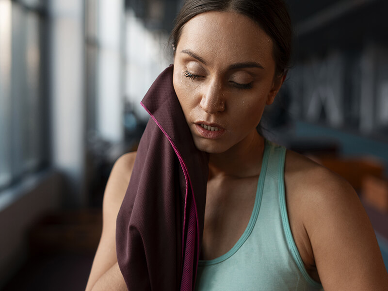 Donna stanca dopo l’allenamento: il momento ideale per applicare un olio corpo defaticante e favorire il recupero muscolare.